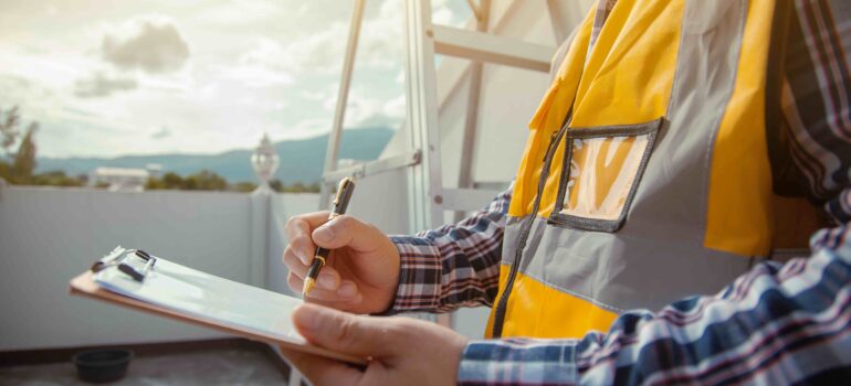 A building surveyor checking and writing down the details of the construction. wearing yellow construction clothes.